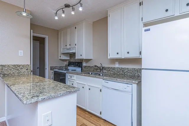 a kitchen with granite countertop white cabinets and white appliances