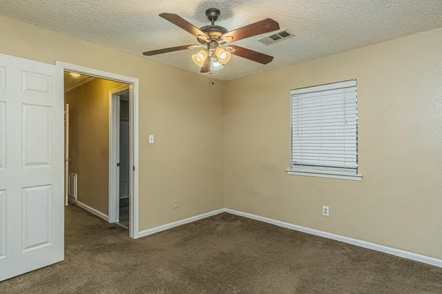 an empty room with windows and fan