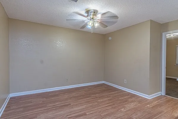 a view of a room with wooden floor and a ceiling fan