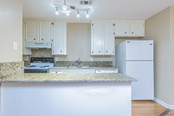 a kitchen with kitchen island granite countertop a refrigerator a stove a sink and white cabinets