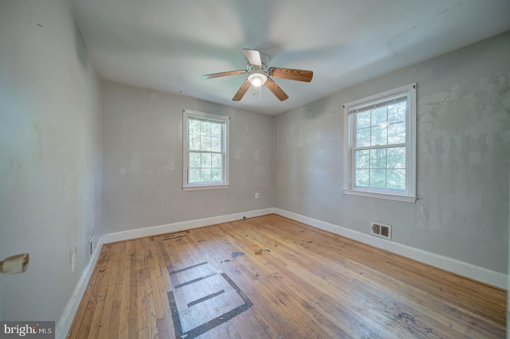 802 Modoc Lane Oxon Hill, MD 20745 - Photo 11 of 34 an empty room with wooden floor ceiling fan and windows