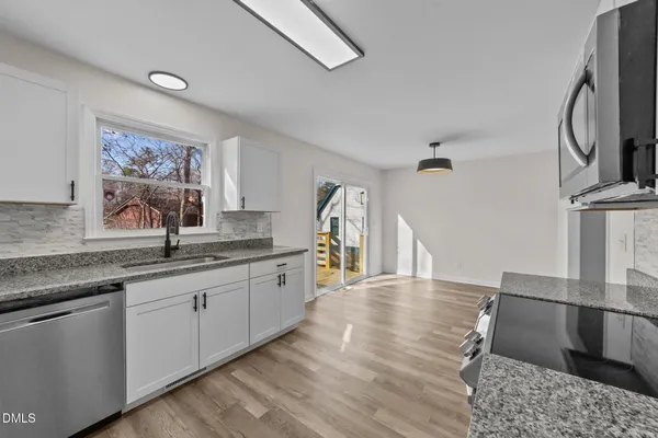 a kitchen with stainless steel appliances granite countertop a sink and wooden floors