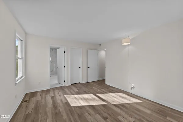 a view of an empty room with wooden floor and window