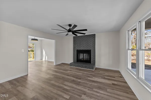 a view of empty room with wooden floor and fireplace