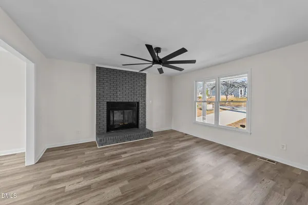 a view of an empty room with a window and fireplace