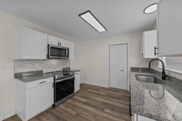 a kitchen with stainless steel appliances granite countertop a stove a sink and a microwave