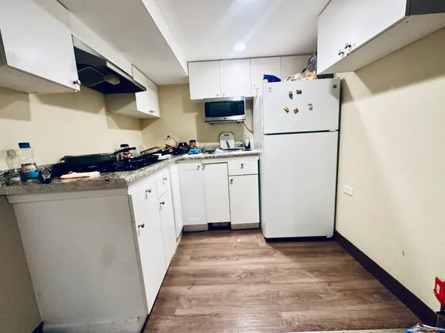 a kitchen with sink a refrigerator and white cabinets