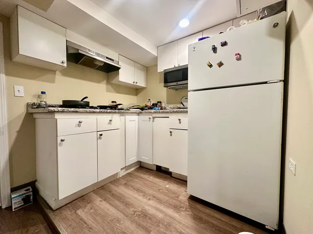 a kitchen with granite countertop white cabinets and white appliances