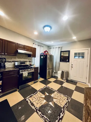 a kitchen with stainless steel appliances kitchen island granite countertop a refrigerator and a stove top oven