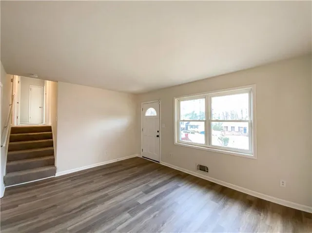 an empty room with wooden floor and windows
