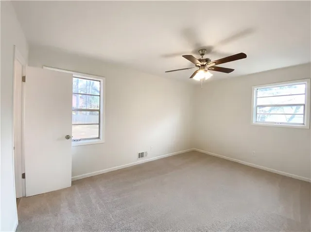 an empty room with a window and a fan