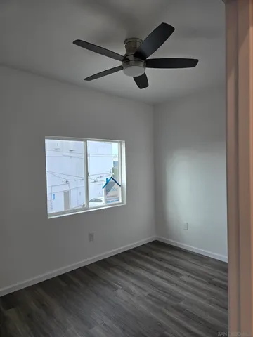 an empty room with wooden floor ceiling fan and windows