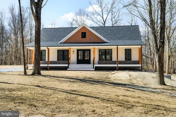 a front view of a house with large trees