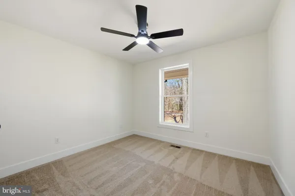 an empty room with ceiling fan and window