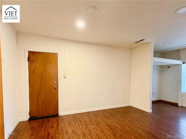 a view of an empty room with wooden floor and closet