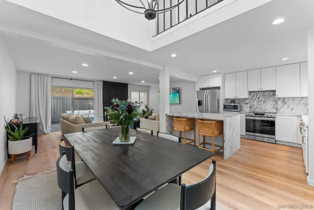 a kitchen with stainless steel appliances kitchen island granite countertop a dining table chairs and white cabinets