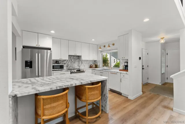 a kitchen with stainless steel appliances granite countertop a table chairs stove refrigerator and microwave