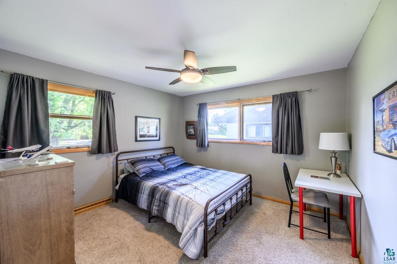 301 2nd Street North Biwabik, MN 55708 - Photo 13 of 43 Carpeted room featuring two windows with wood trim, a ceiling fan with integrated lighting, and light gray walls