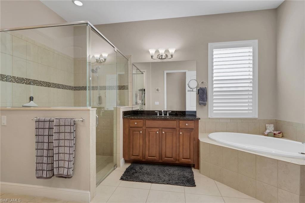 1589 Serrano Circle Naples, FL 34105 - Photo 17 of 38 a bathroom with a bathtub a sink a mirror and a shower