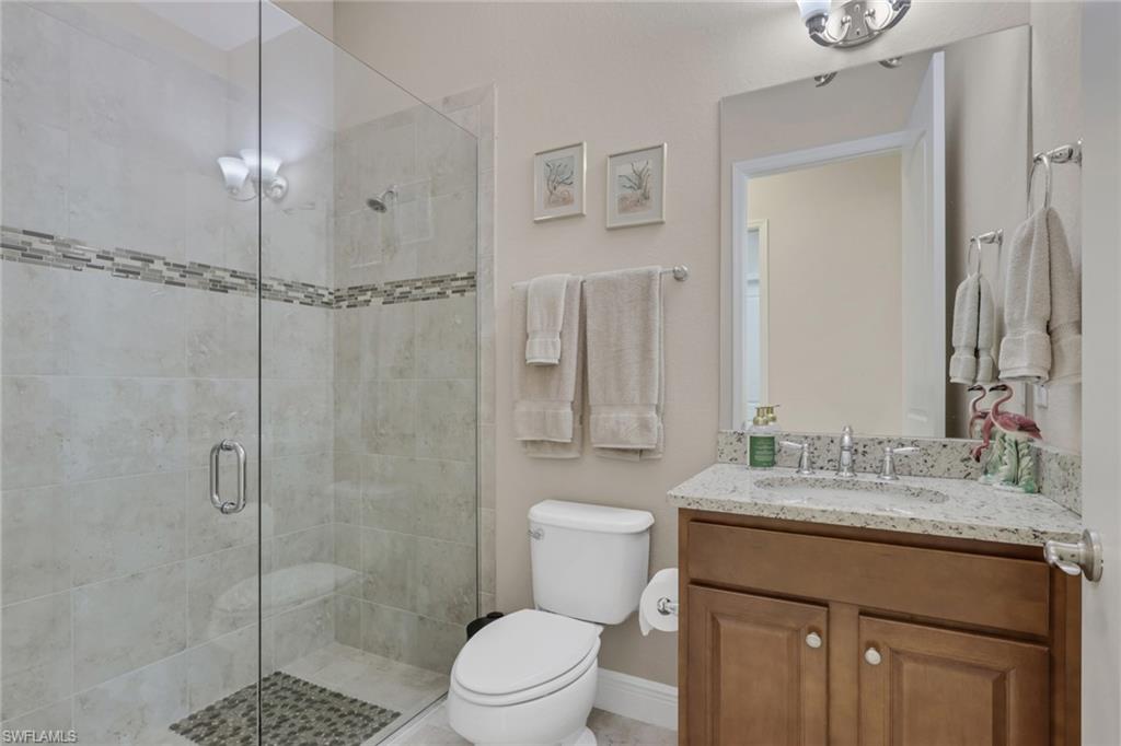 1589 Serrano Circle Naples, FL 34105 - Photo 22 of 38 a bathroom with a granite countertop sink a toilet and shower