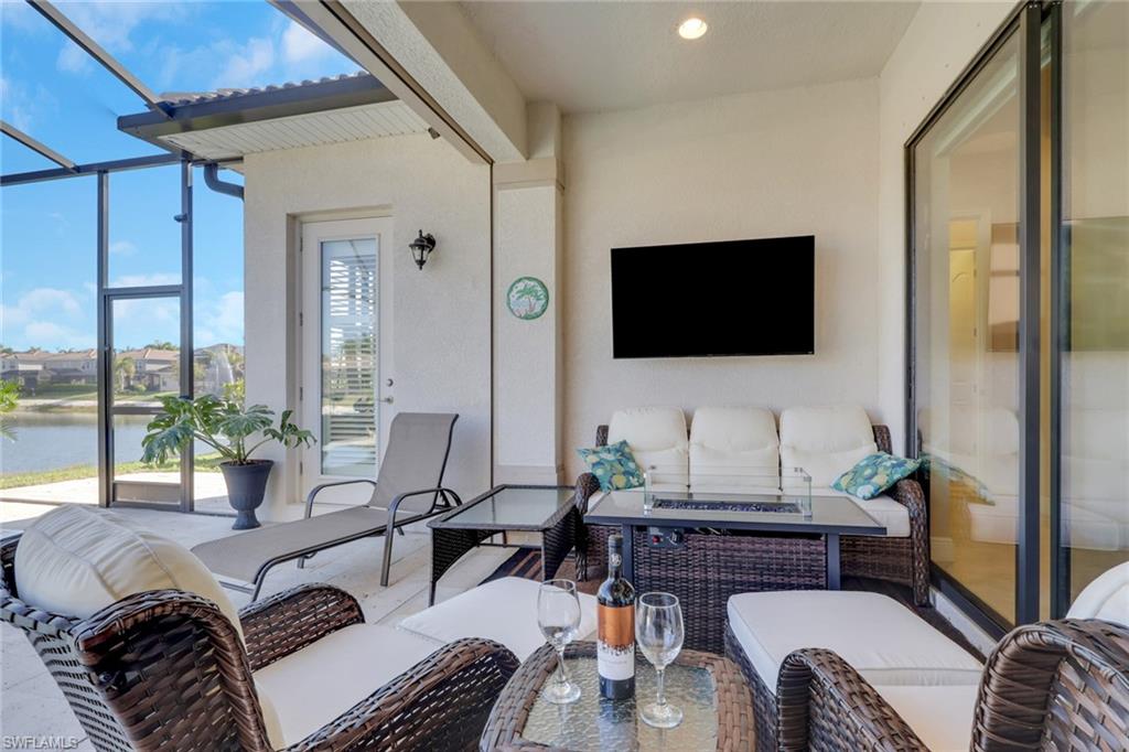 1589 Serrano Circle Naples, FL 34105 - Photo 29 of 38 a living room with furniture a flat screen tv and a floor to ceiling window