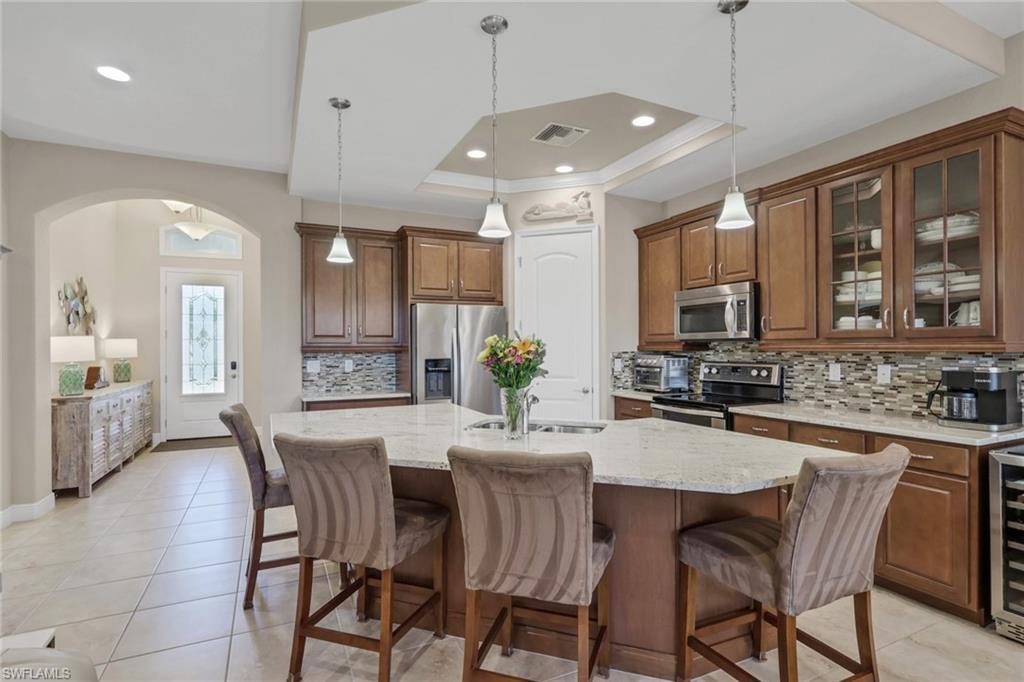1589 Serrano Circle Naples, FL 34105 - Photo 5 of 38 a kitchen with granite countertop a stove a sink a dining table and chairs