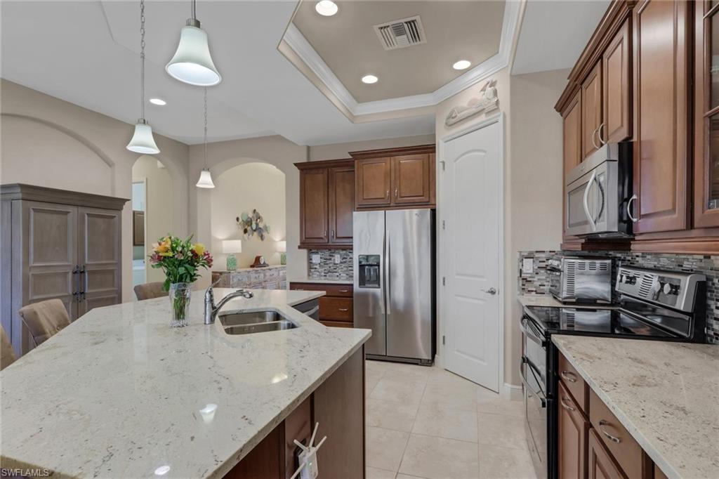 1589 Serrano Circle Naples, FL 34105 - Photo 6 of 38 a kitchen with stainless steel appliances granite countertop a sink a stove and a refrigerator