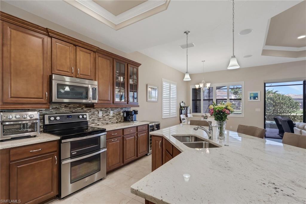 1589 Serrano Circle Naples, FL 34105 - Photo 7 of 38 a kitchen with stainless steel appliances granite countertop a stove top oven a sink dishwasher a dining table and chairs with wooden floor