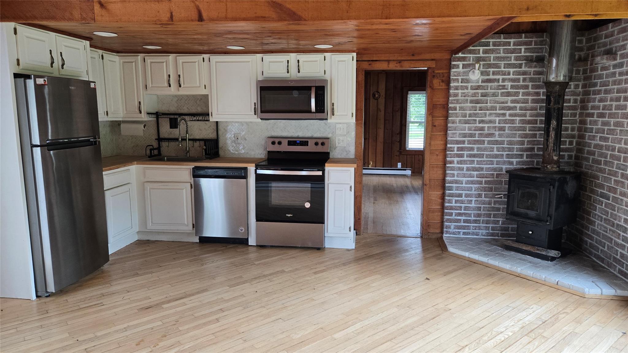 1139 State Rt 17B Mongaup Valley, NY 12762 - Photo 2 of 35 Kitchen featuring light wood-style flooring, stainless steel appliances, white cabinetry, decorative backsplash, and wood ceiling