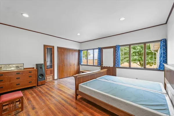 a spacious bedroom with a bed and wooden floor