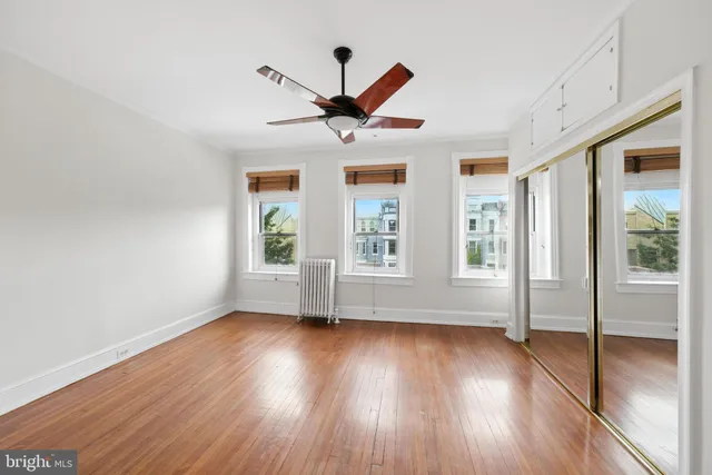 a view of n empty room with window and wooden floor