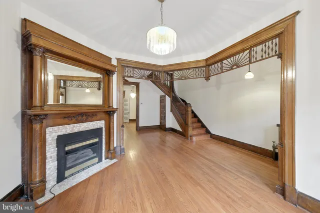 a view of an empty room with wooden floor a fireplace and a window