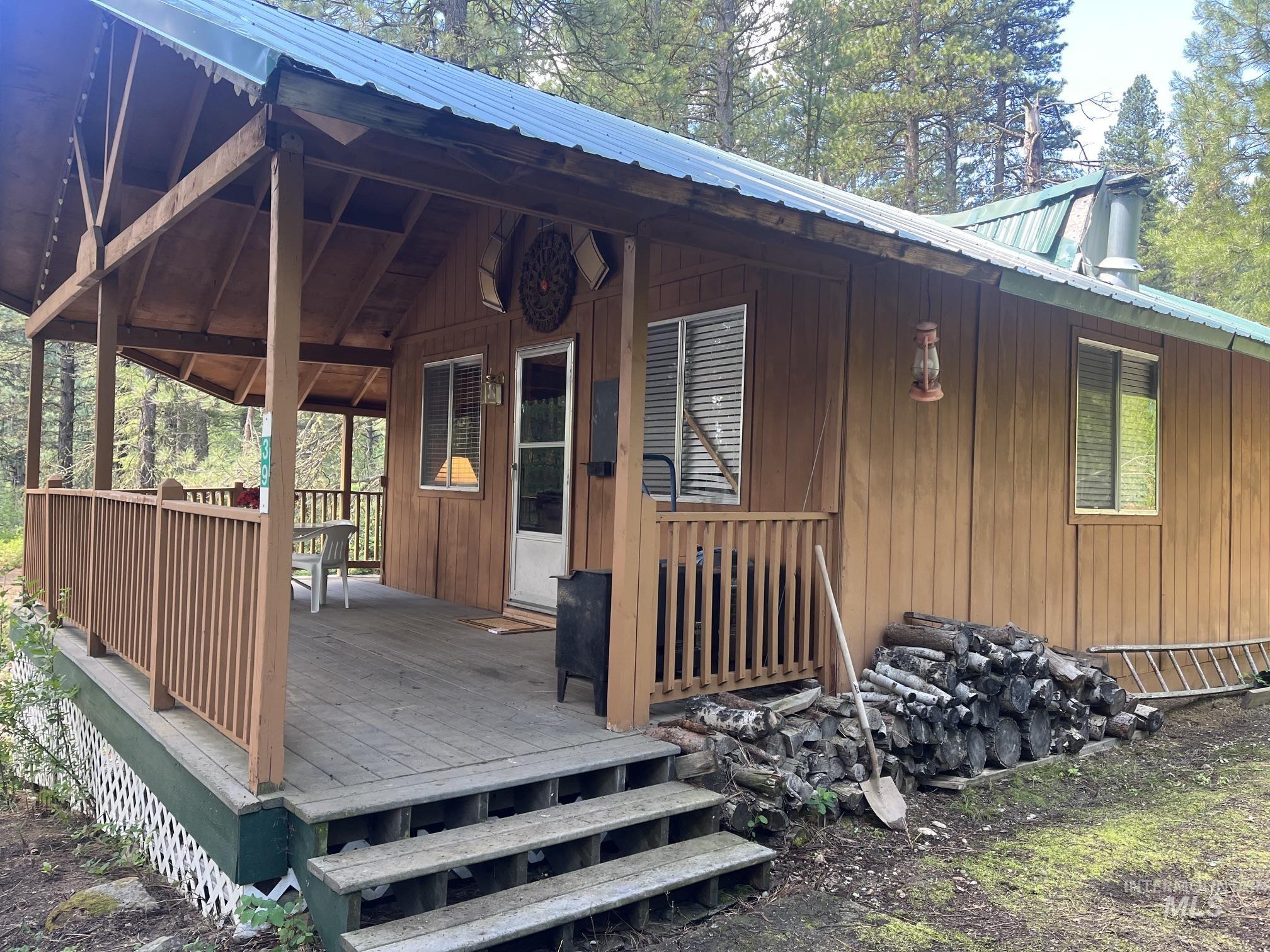 39 Mayflower Mine Road Placerville, ID 83666 - Photo 3 of 36 Exterior featuring wood-finish siding, a covered porch with wooden railings, a metal roof, and visible window units