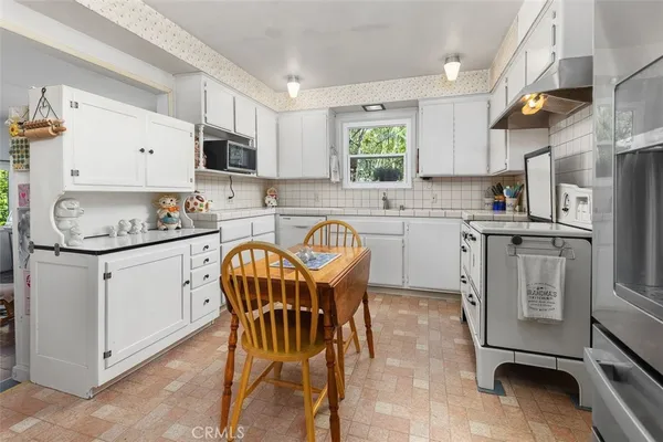 a kitchen with stainless steel appliances granite countertop a white table chairs and a refrigerator