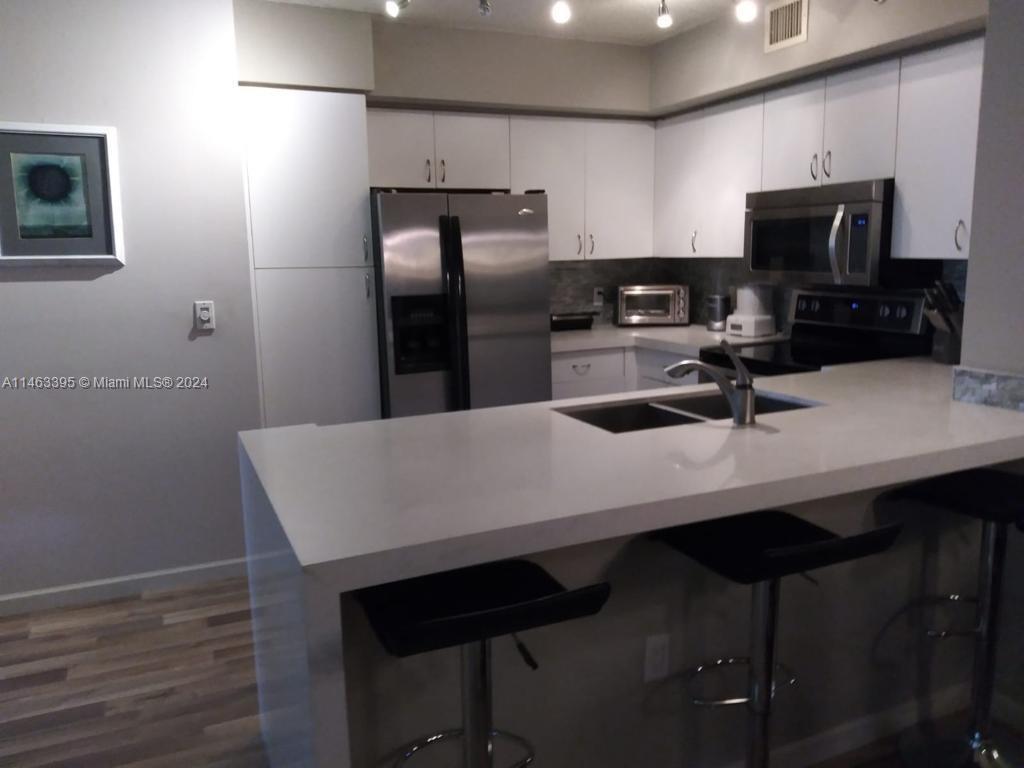 a kitchen with stainless steel appliances a kitchen island hardwood floor sink and stove