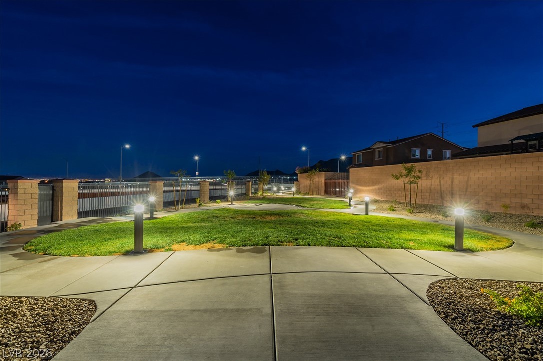 6444 Spring Jog Street Las Vegas, NV 89166 - Photo 13 of 13 Illuminated pathways guide you through this serene outdoor space with mountain views under a twilight sky.