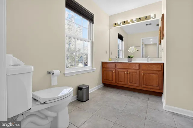 a bathroom with a granite countertop toilet a sink and a mirror