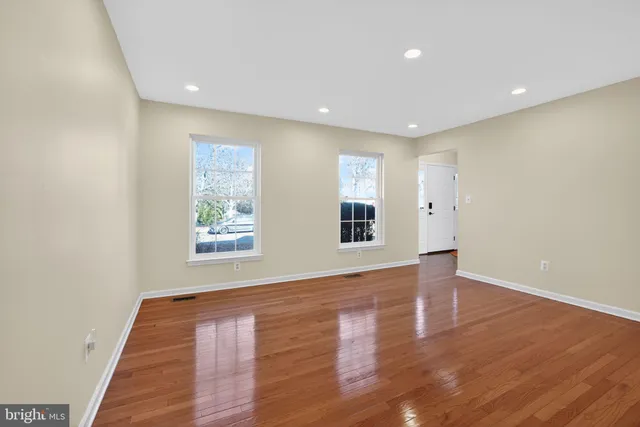a view of an empty room with wooden floor and windows