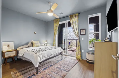a bedroom with a bed wooden floor and a flat tv screen on a dresser