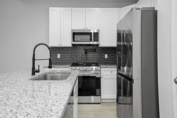 a kitchen with stainless steel appliances granite countertop a sink stove and refrigerator