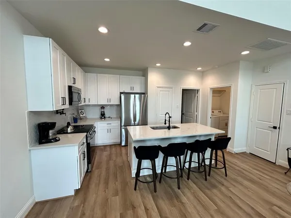 a kitchen with refrigerator a sink and wooden floor