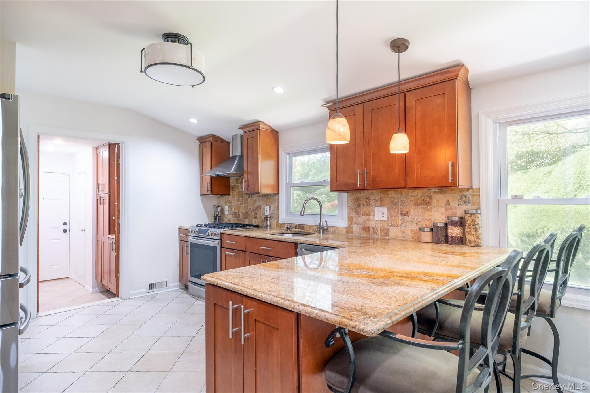 24 Sheldrake Place New Rochelle, NY 10804 - Photo 8 of 26 Kitchen with stainless steel appliances, a sink, wall chimney range hood, brown cabinets, and backsplash
