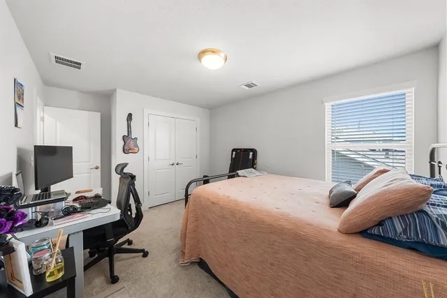 a bedroom with a bed and a computer on the desk