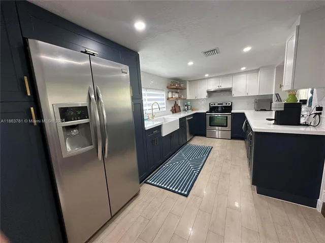 a kitchen with stainless steel appliances granite countertop a refrigerator and a sink