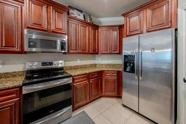 a kitchen with granite countertop a refrigerator stove and microwave