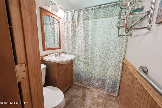 a bathroom with a sink a toilet a mirror and shower curtain