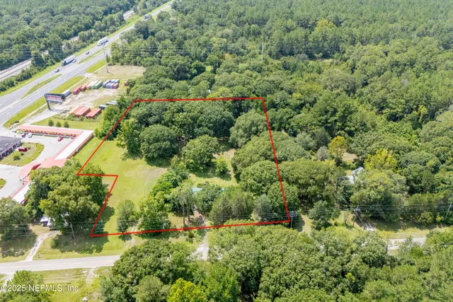 an aerial view of residential house with outdoor space and trees all around