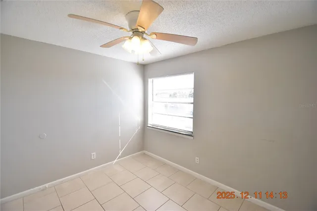 an empty room with windows and fan