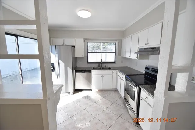 a kitchen with granite countertop a stove a sink and a refrigerator