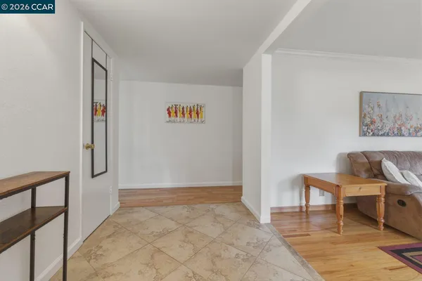 a view of a hallway with wooden floor and a living room